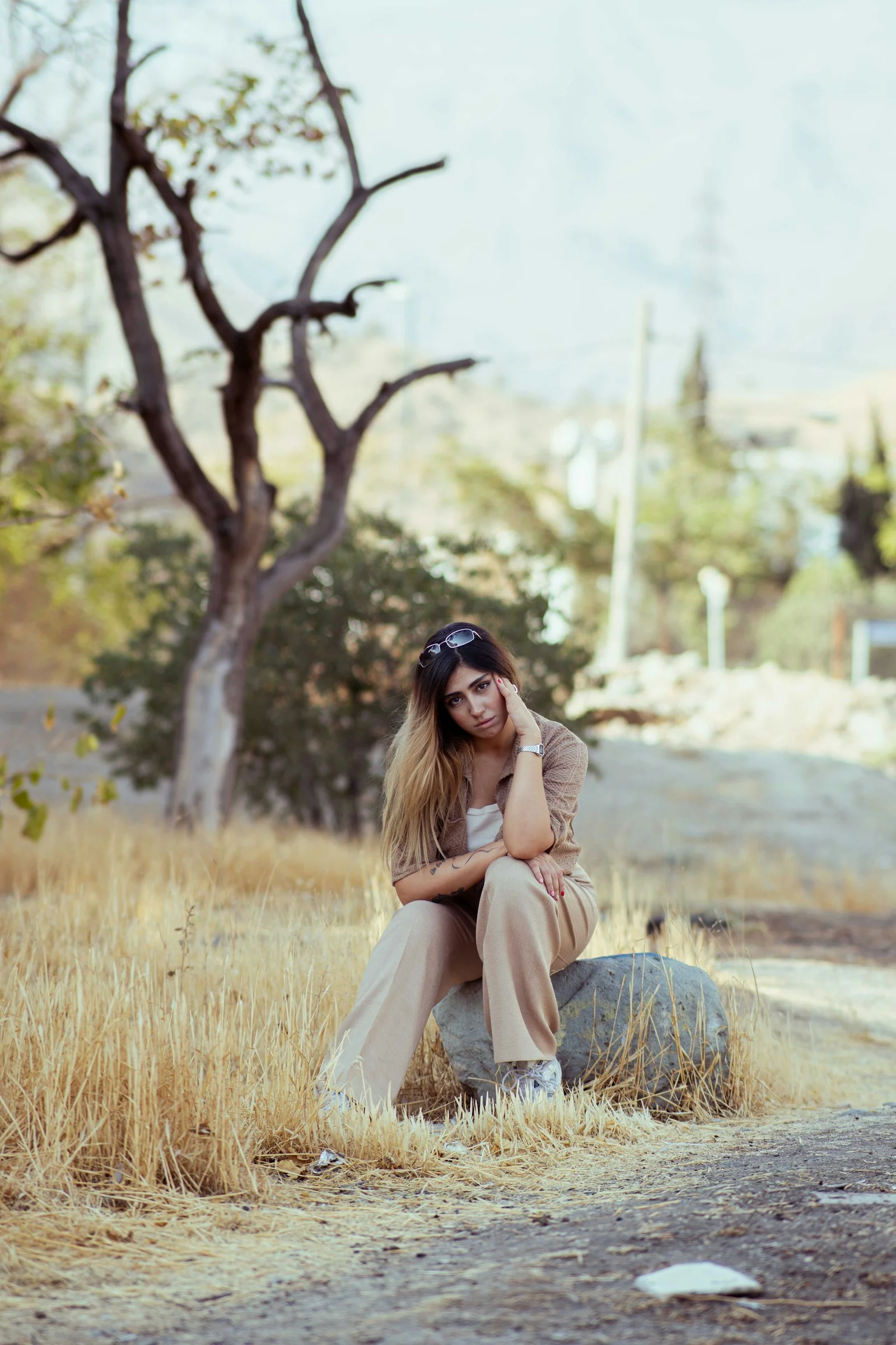 Woman sitting on rock in dry grassy field