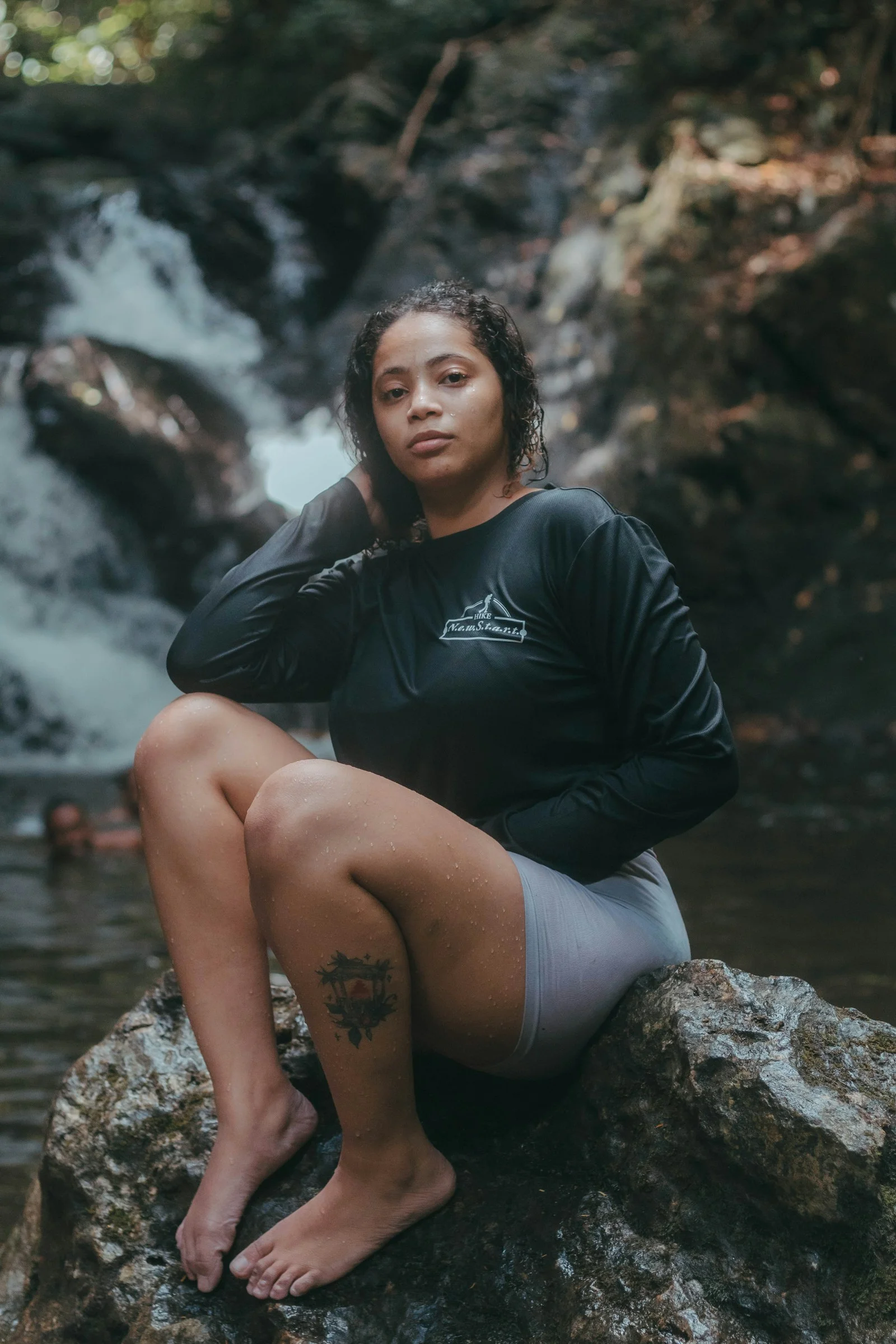 a woman sitting on a rock in front of a waterfall