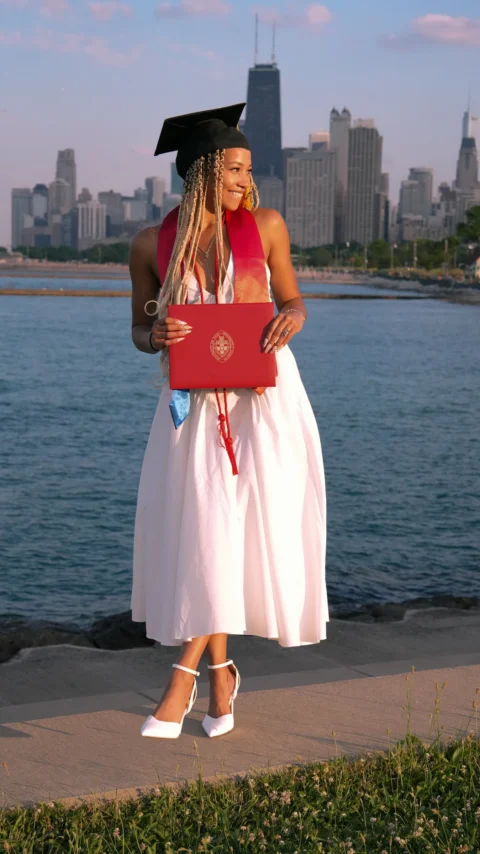 A woman in a graduation gown holding a laptop