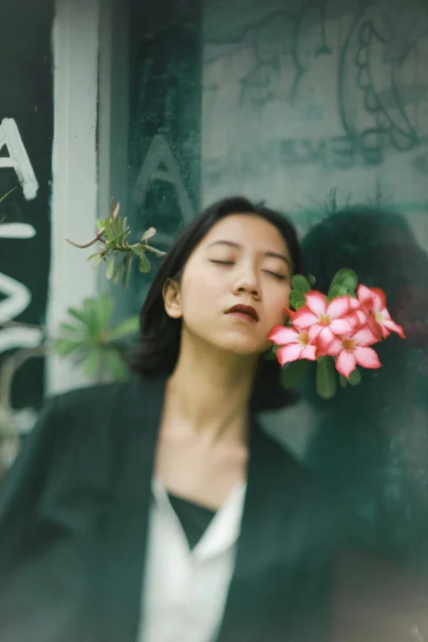 穿黑色西裝外套、手拿紅花的女子