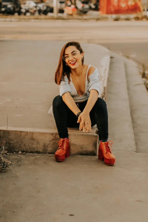 a woman sitting on a curb smiling at the camera