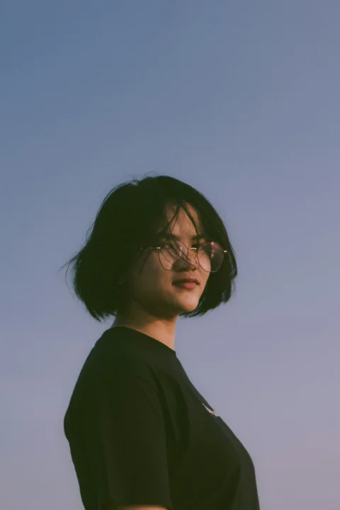 一位戴眼鏡的女子站在藍天前