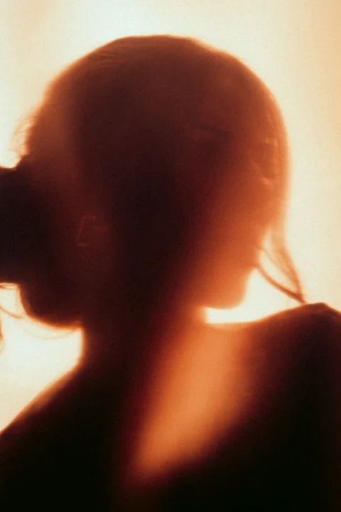 A silhouette of a woman drinking from a bottle