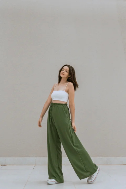 a woman in a white top and green pants