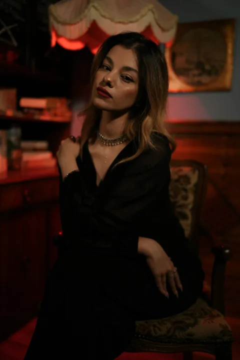 A woman in a black blouse sitting in a chair under red light