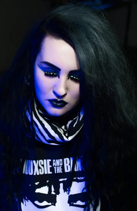 a woman with long black hair and blue makeup