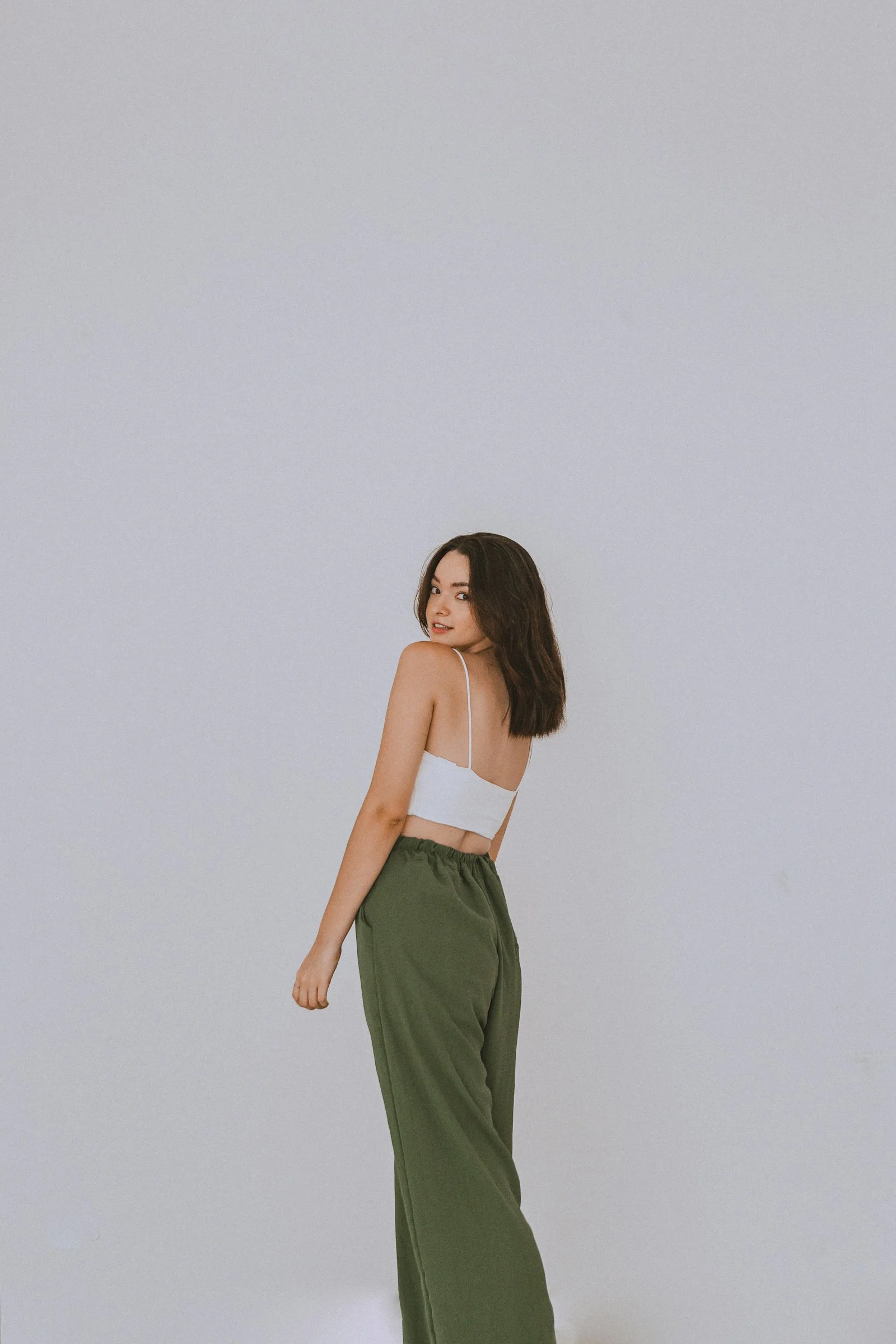 a woman in a white top and green pants