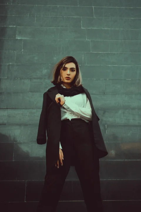 woman in black long sleeve dress standing beside gray wall