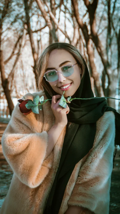 woman in brown fur coat holding green and white rose