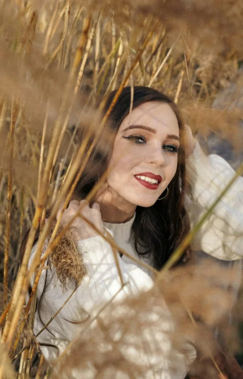 Young woman with dark hair smiling in tall dry grass