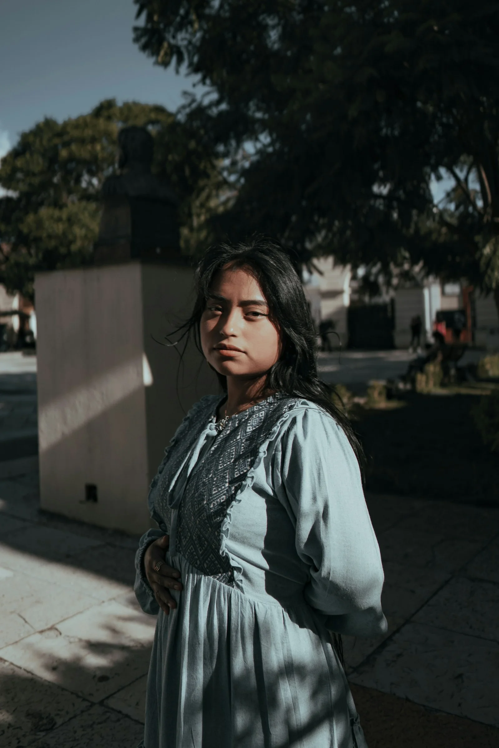 A woman poses outdoors in a pretty dress