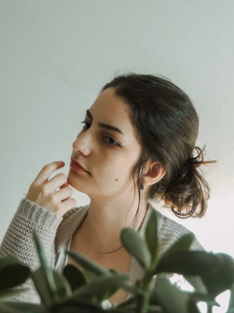 woman in green blazer holding her face