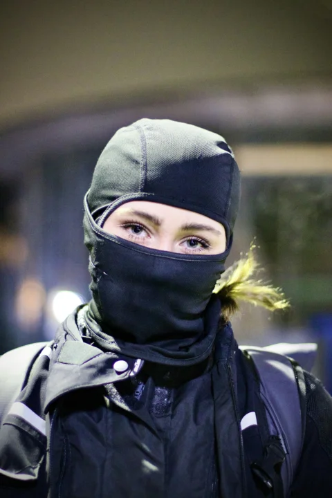 A person in a balaclava looks at the camera