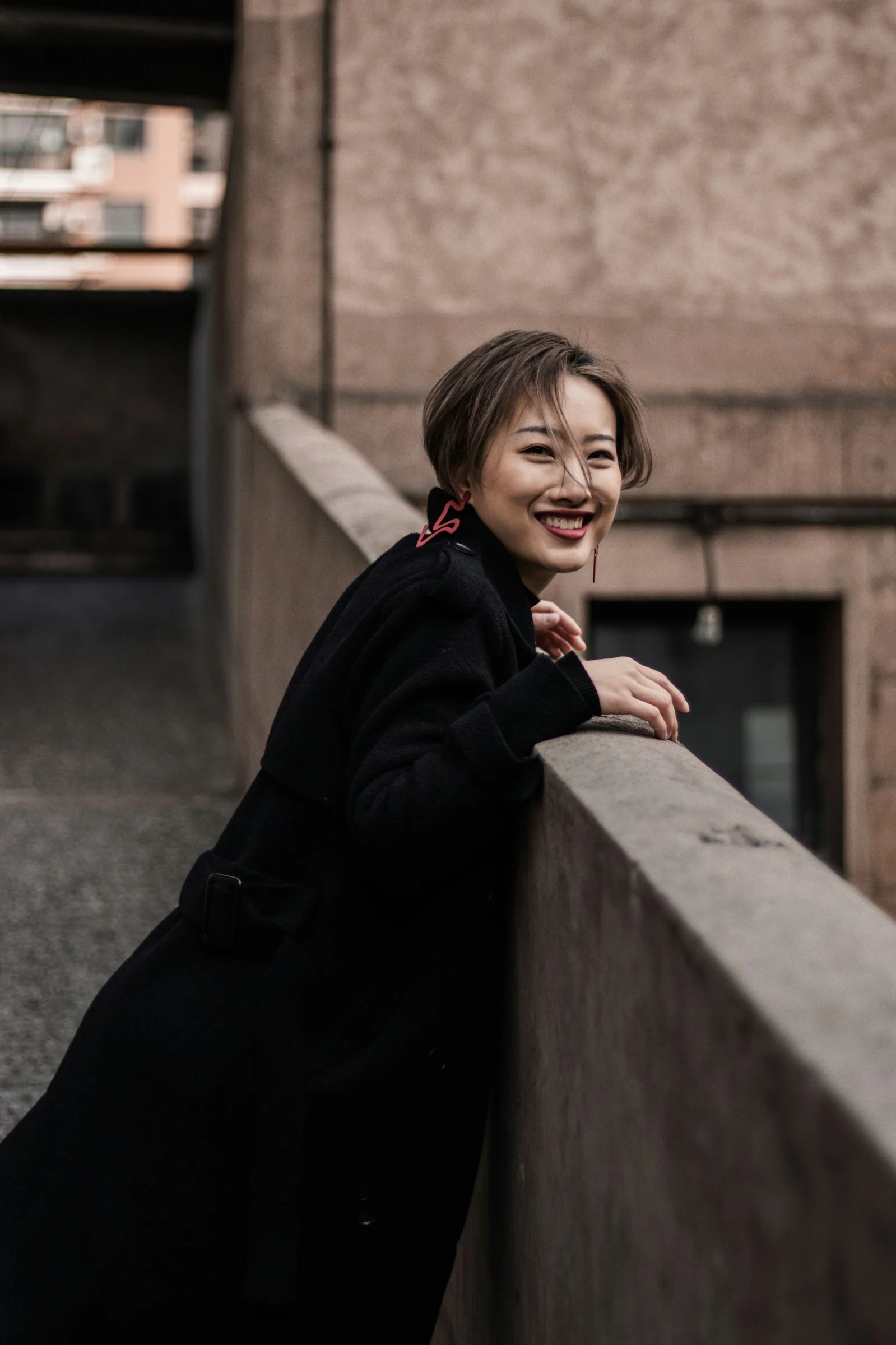 낮에 콘크리트 벽에 기대고 있는 검은 재킷을 입은 여성