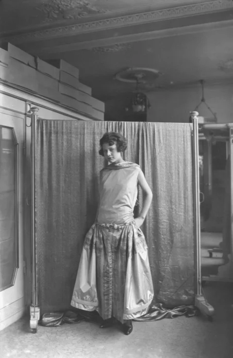 a woman standing in front of a curtain in a room