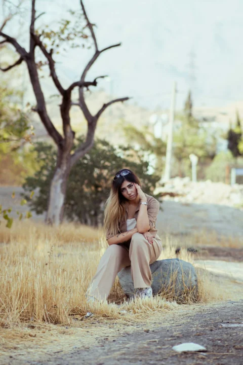Woman sitting on rock in dry grassy field