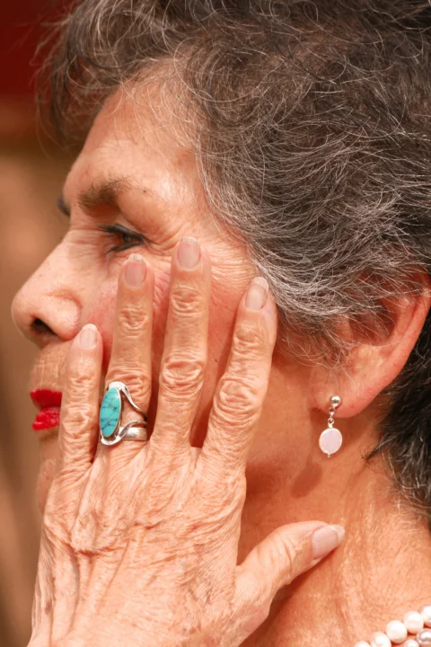 an older woman holding her hands to her face
