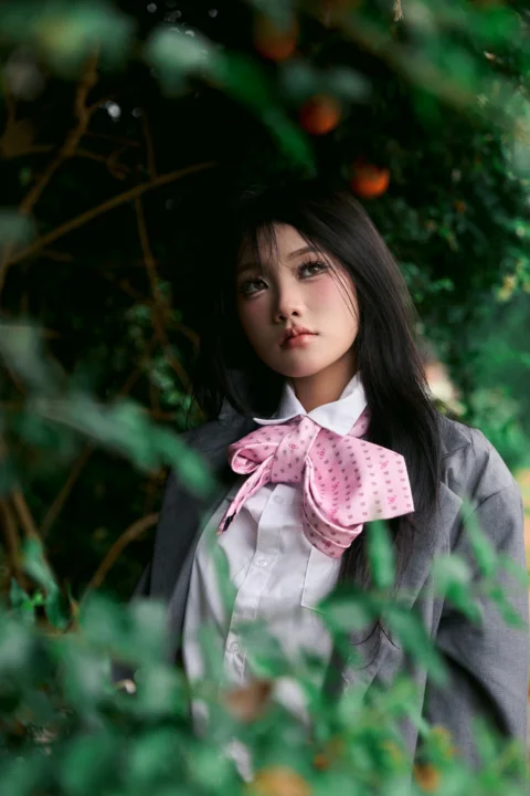 Young woman in school uniform surrounded by green foliage