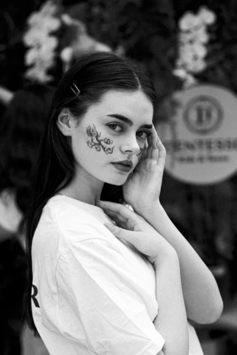 A woman with face paint talking on a cell phone