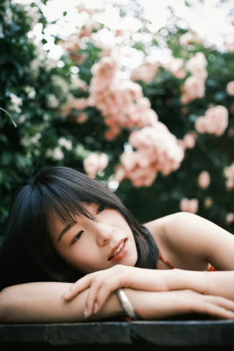 Young woman resting her head on arms with pink flowers