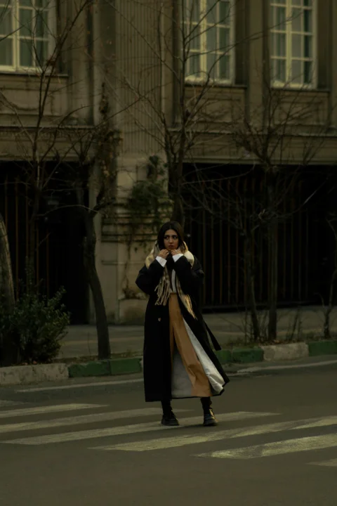 A woman walking across a street talking on a cell phone