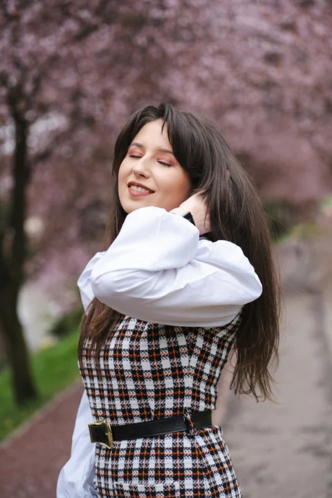 Woman smiles amidst blooming trees in spring