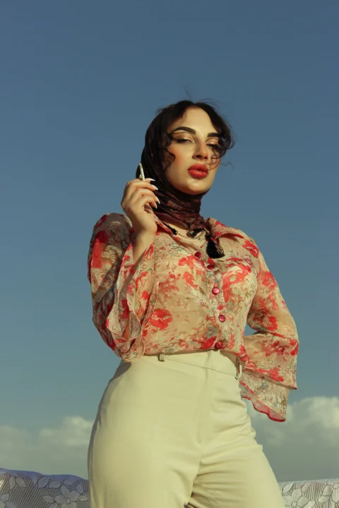 a woman in a floral shirt is holding a cell phone
