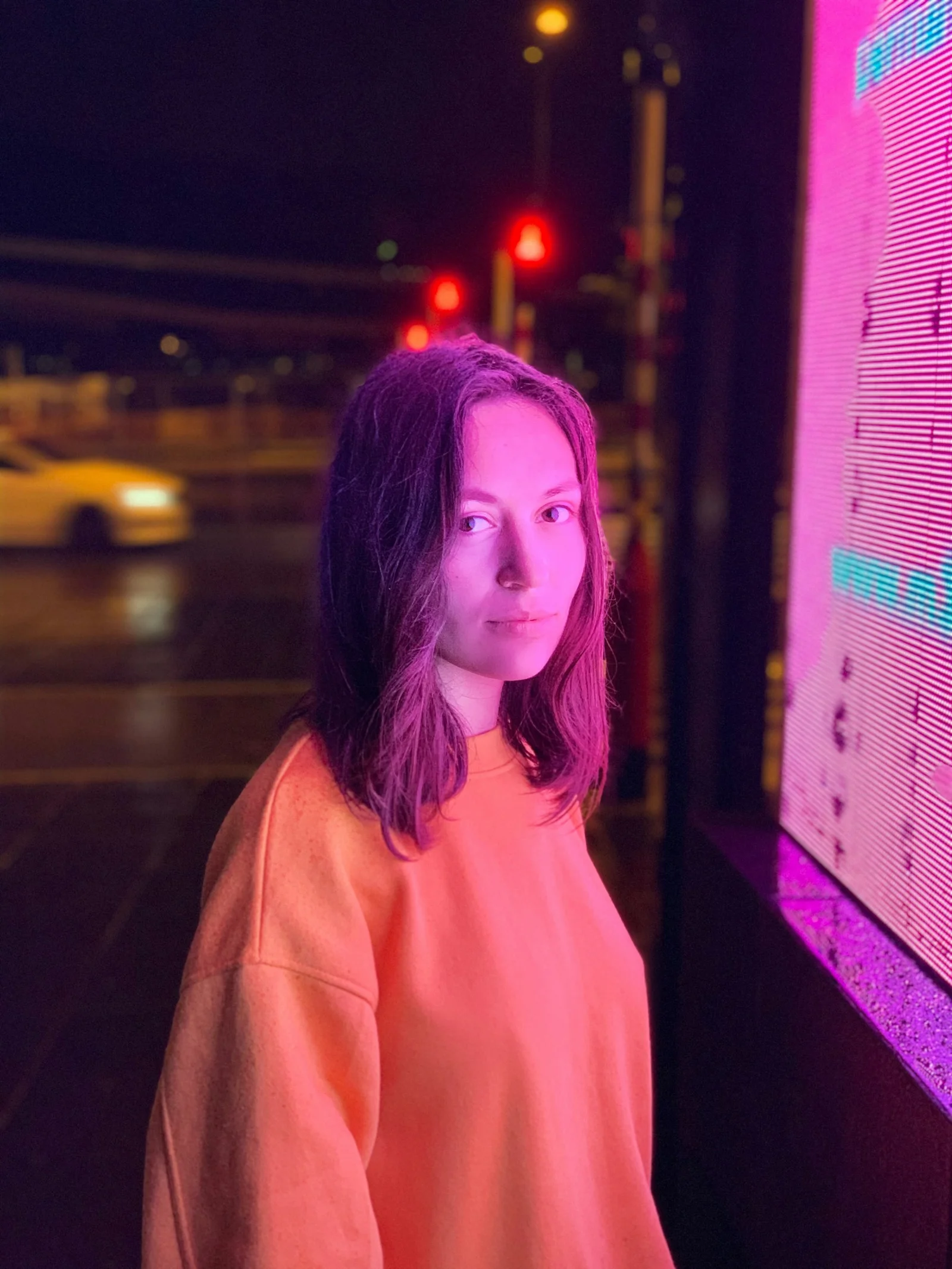 woman wearing orange sweatshirt standing in front of LED wall