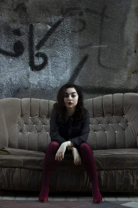 a woman sitting on a couch in front of a graffiti covered wall