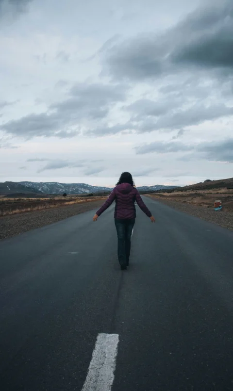 a woman walking down the middle of a road