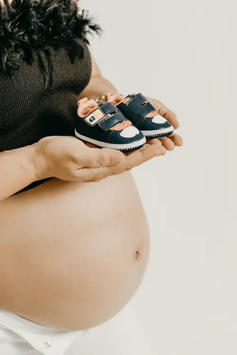 ベビーシューズを手に持った妊娠中の女性