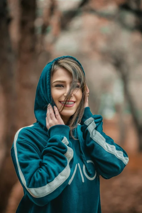 选择性对焦摄影中微笑着穿蓝色连帽衫的女子