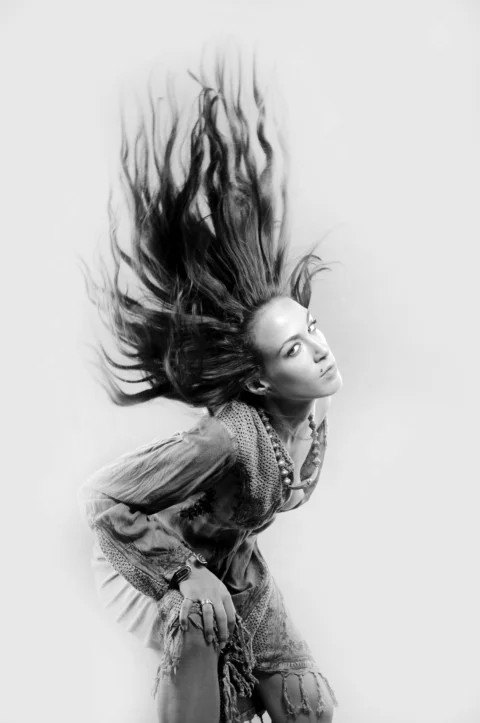 A black and white photo of a woman with her hair blowing in the wind