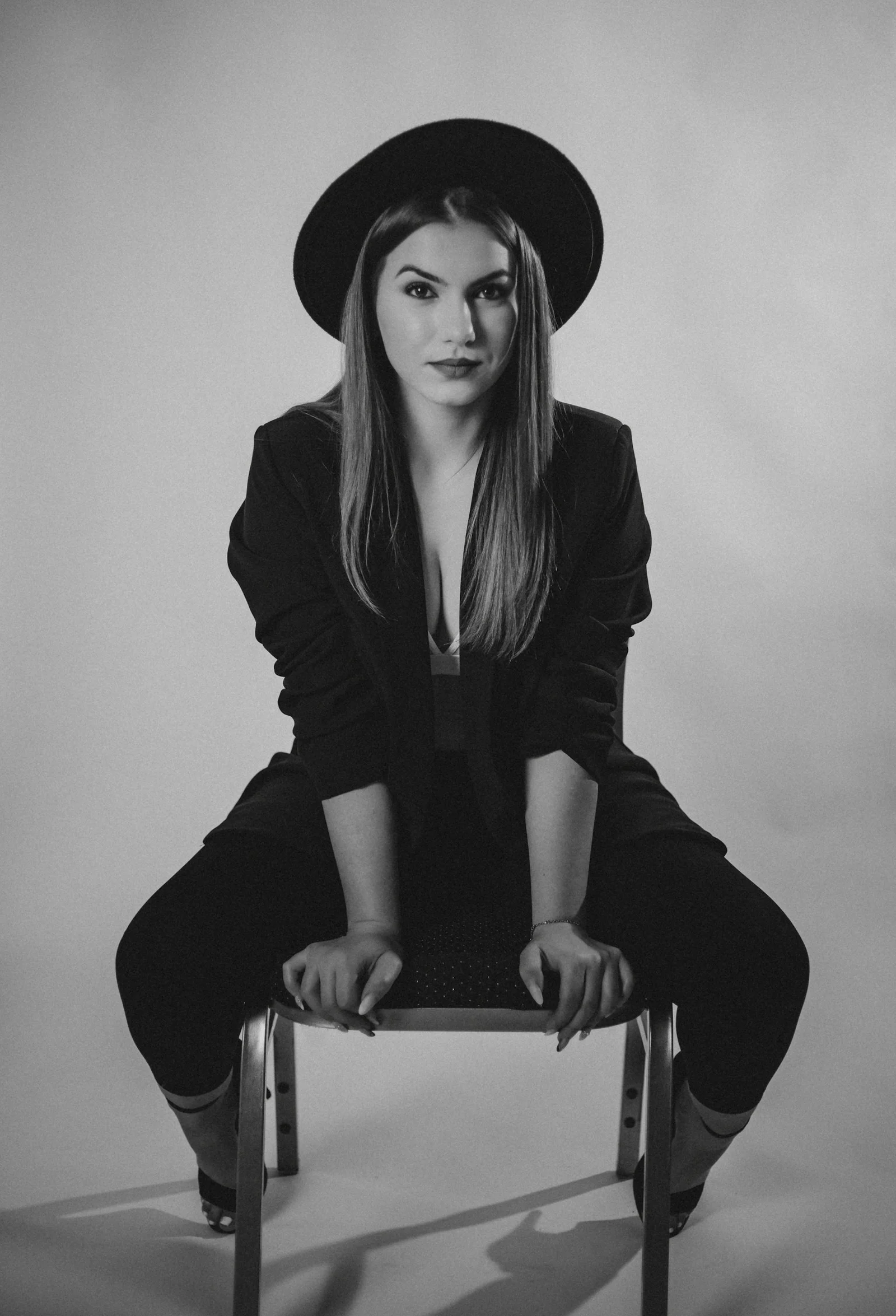 Woman in a hat and suit sits on a chair