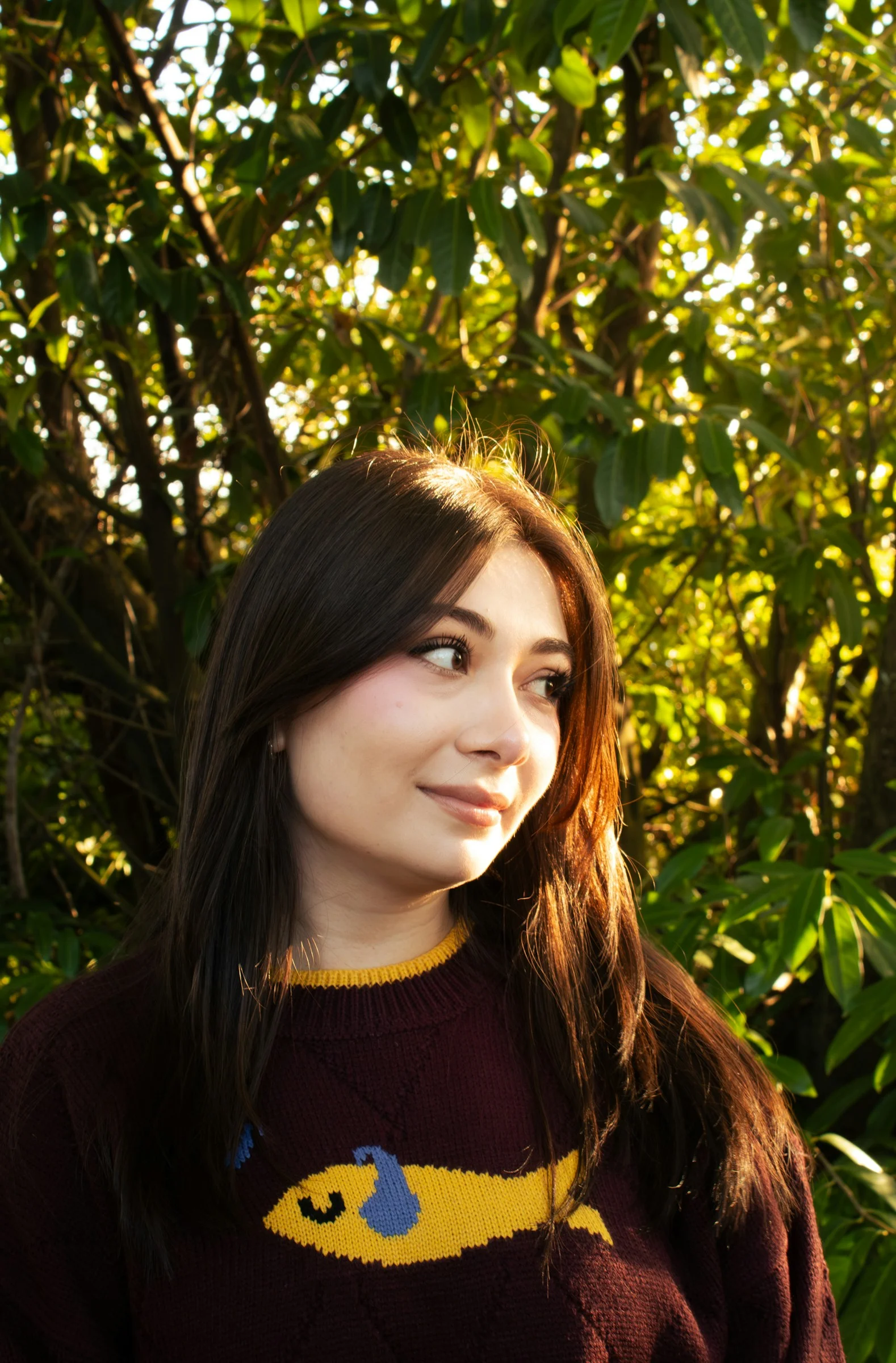 Young woman with dark hair wearing a sweater outdoors