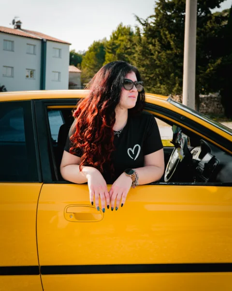 Woman with long hair looks out of a yellow car