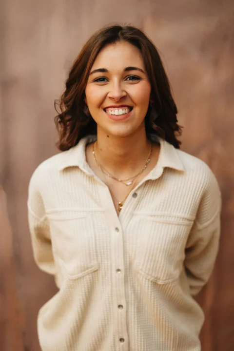 A smiling woman poses in front of a wall