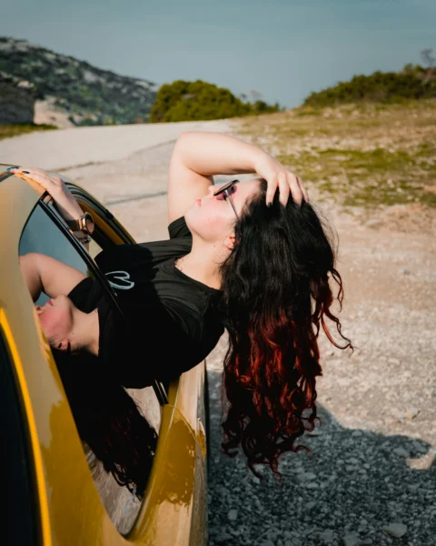 A woman enjoys the wind outside the car