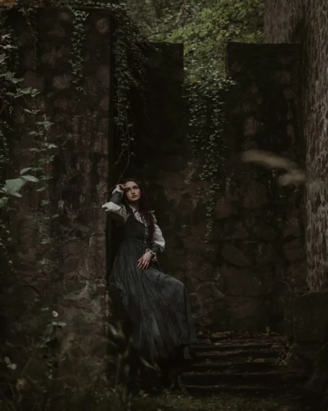 a woman in a black dress is sitting on a stone staircase
