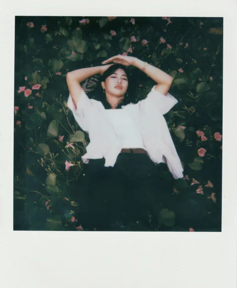 Young woman lying in green foliage with pink flowers