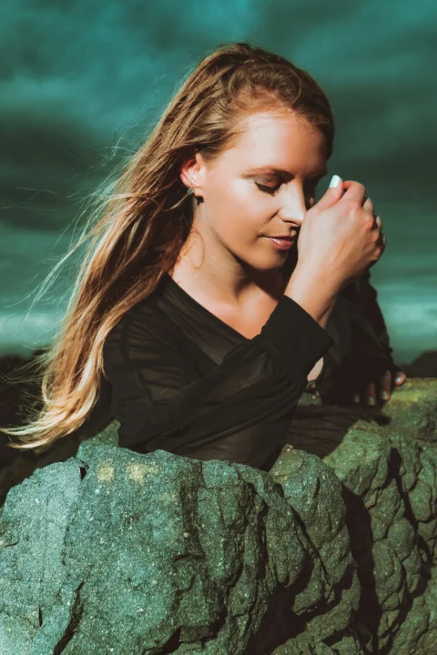 woman in black long sleeve shirt sitting on rock
