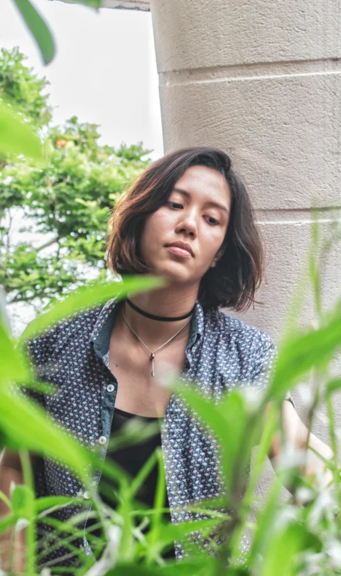 白墙旁低头站立的女子