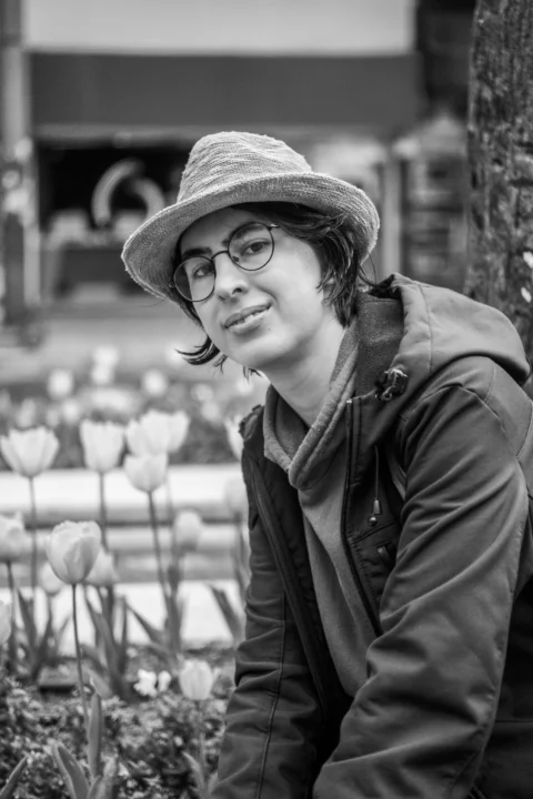 Person in hat and glasses next to tulips
