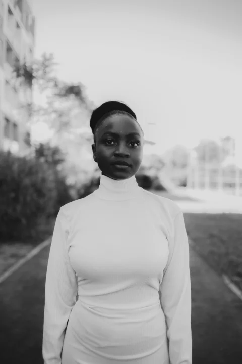 A young black woman in a white turtleneck outdoors