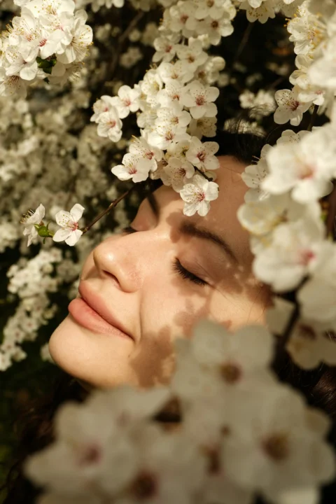 一位闭着眼睛的女性被白色花朵环绕