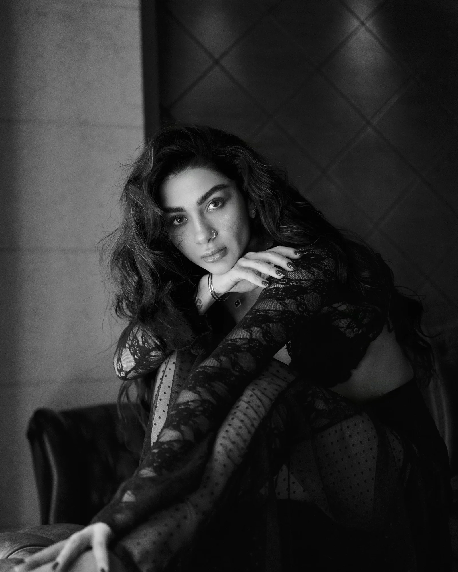 A woman poses elegantly in black lace