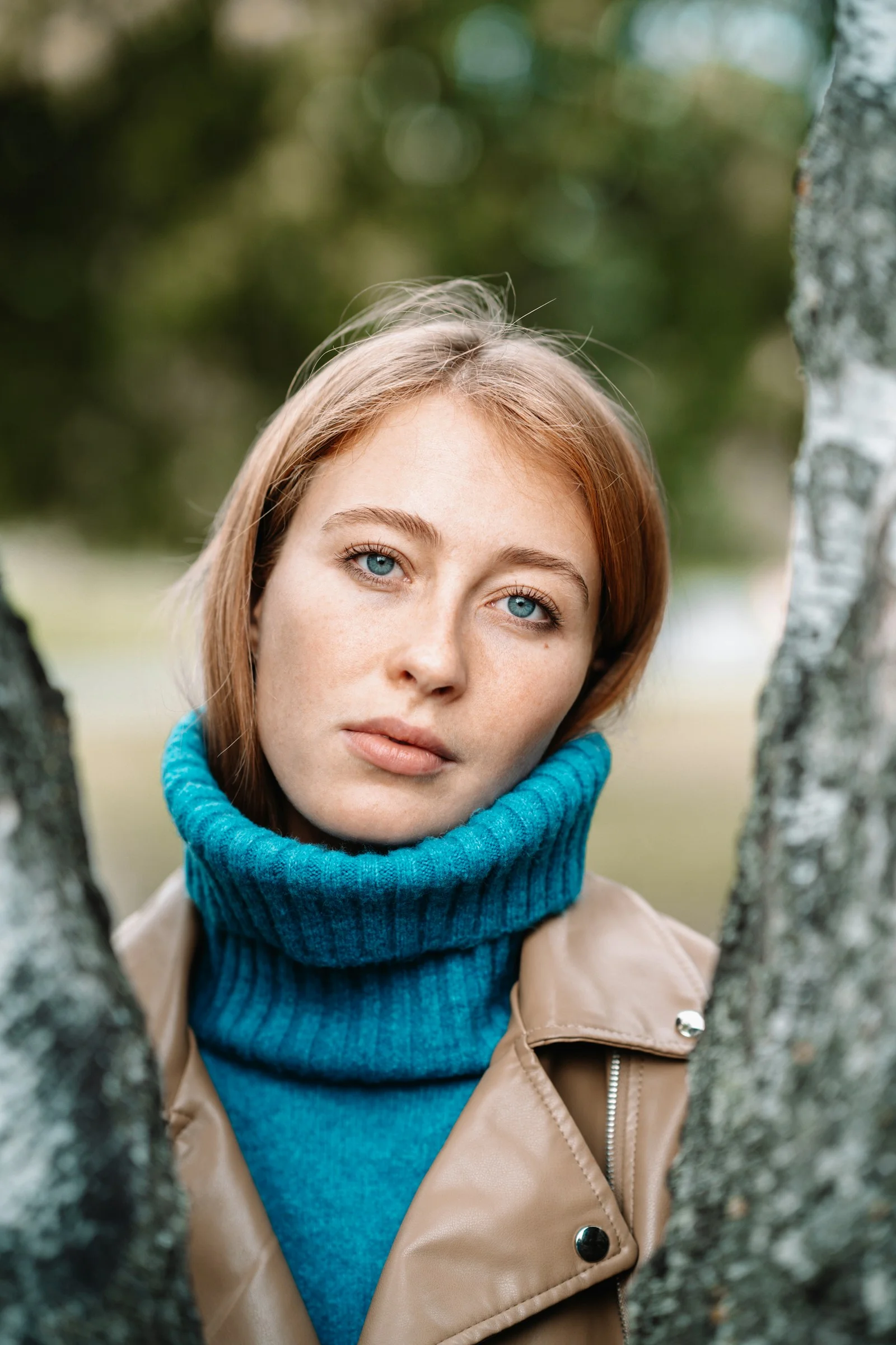 A woman with red hair looks between trees