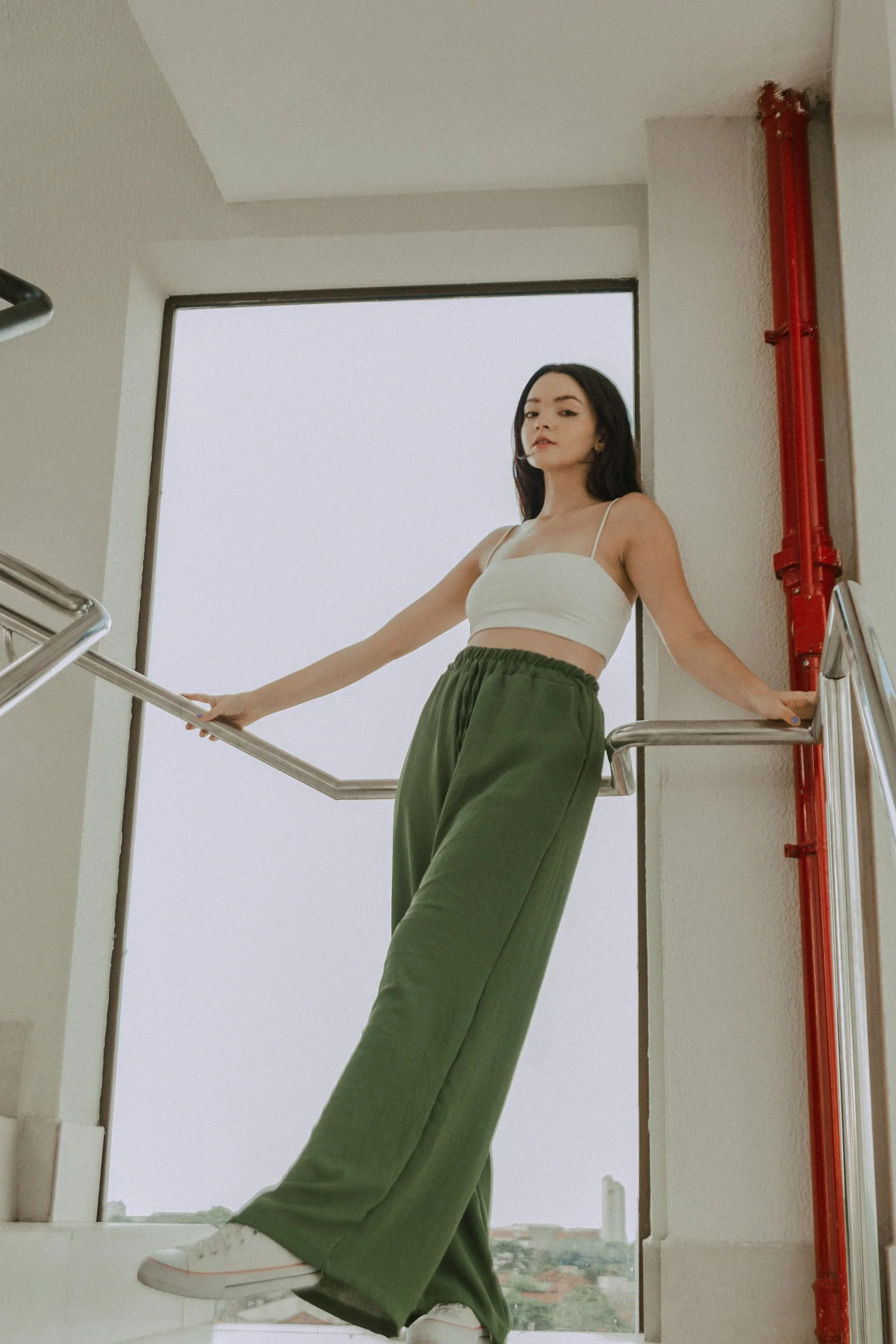 a woman in a white top and green pants
