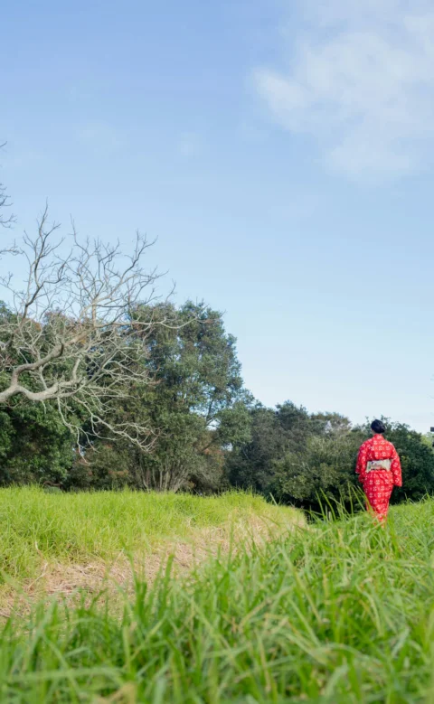 Person in red kimono walking through a grassy field
