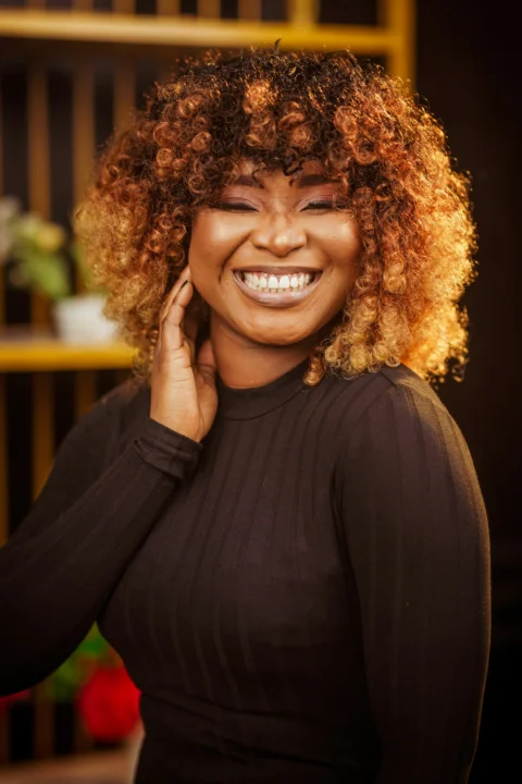 A woman smiles joyfully with beautiful curly hair